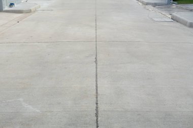 Beton kaldırım manzarası, yerleşim yerindeki yol, genişleme eklemleri. İnşaat endüstrisi malzemeleri, altyapı geliştirme ve ulaşım yüzeyi sunar.