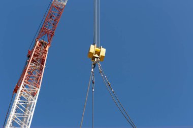 İnşaat alanında ağır yük kaldırmak için çelik halat saplı ağır vinç kancası. Vinç kolunun çelik kiriş çerçevesini de dahil et. Endüstriyel kaldırma ekipmanları ve inşaat makinelerini temsil ediyor.