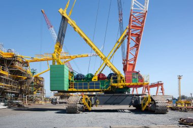 İnşaat alanında dev bir vinç ya da sürüngen vinci, mekanik çerçeveli yan görüş ve bum. Ağır kaldırma makineleri inşaat, mühendislik, güç ve sanayi altyapısını temsil ediyor.