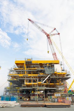 Petrol platformu için çelik yapı inşaatında çalışan büyük bir vinç. Doğal kaynakları keşfetmek için kıyı ötesi sondaj projelerinde ağır yükü kaldırmak için endüstriyel makine ekipmanları.