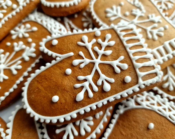 gingerbread cookies Christmas gloves decorated with royal icing, with icing sugar as background. Christmas food, pastry background. New Year theme. Merry Christmas and Happy New Year Holidays greeting