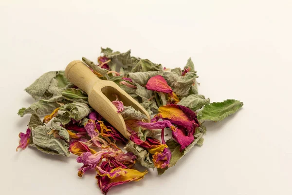 Dry tea mint, rose leaves in a wooden spoon on white background. Detox and immunity tea.