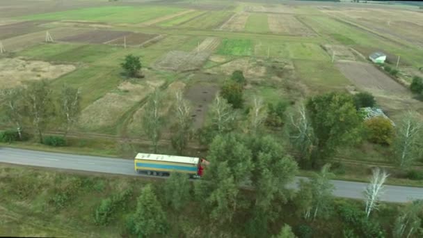 卡车在乡间路上开着车 一辆装有蓝色和黄色拖车的红色卡车沿着它的航线飞行4K — 图库视频影像