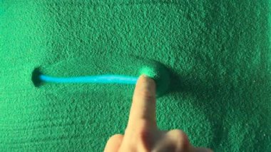 Hand drawing the right arrow in the Green Sand. Male hand writes the right arrow on the green sand with blue backlight. Top view 4k resolution