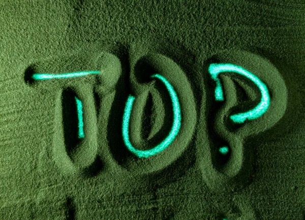 Hand drawing the Word Top in the Green Sand. Male hand writes the word Top on the green sand with blue backlight. Top view 6k resolution