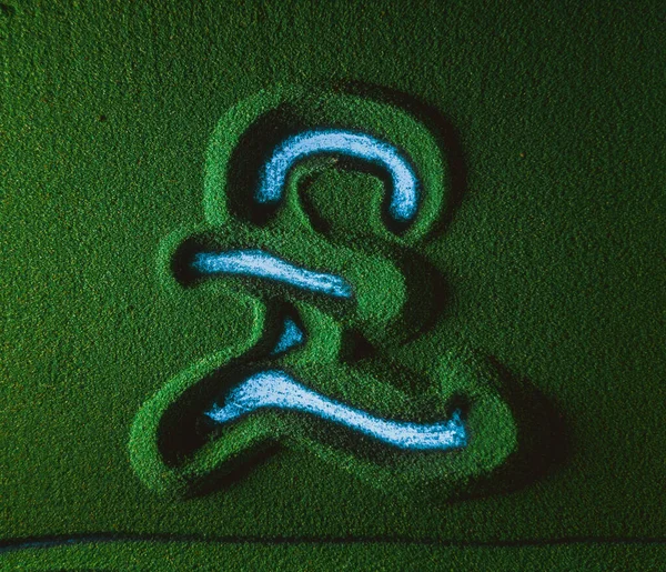 Hand drawing the Pound currency symbol in the Green Sand. Male hand writes the Pound currency symbol on the green sand with blue backlight. Top view 4k resolution
