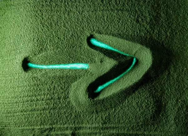 Hand drawing the right arrow in the Green Sand. Male hand writes the right arrow on the green sand with blue backlight. Top view 4k resolution