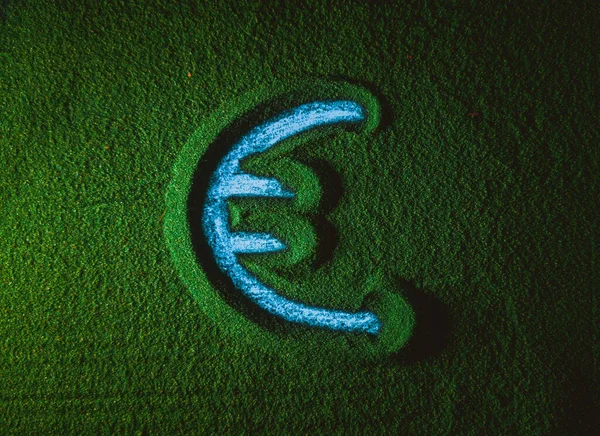 Hand drawing the Euro currency symbol in the Green Sand. Male hand writes the Euro currency symbol on the green sand with blue backlight. Top view 4k resolution