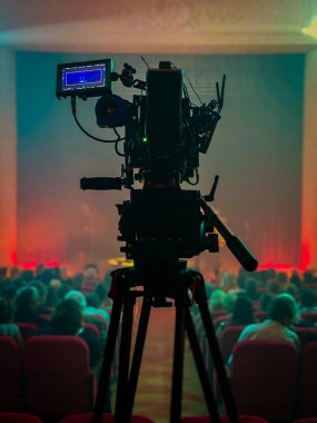 Konser salonunun ortasında tripodun üzerinde duran bir film kamerası etkinliği bekliyor.