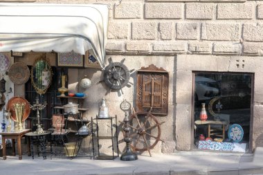 Antika dükkanında taş bir duvarın önünde satılık eski ve otantik eşyalar sergileniyor..