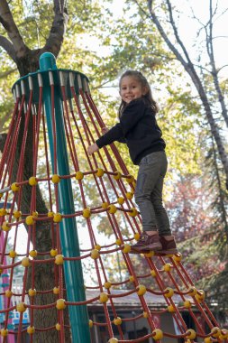 Siyah tişörtlü sarışın küçük kız oyun parkında tek başına oynuyor. Seçici Odaklanma Kızı.