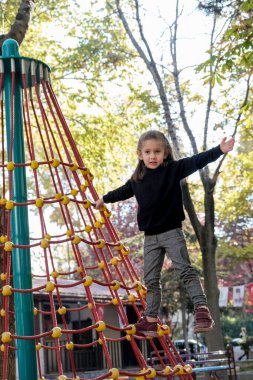 Siyah tişörtlü sarışın küçük kız oyun parkında tek başına oynuyor. Seçici Odaklanma Kızı.