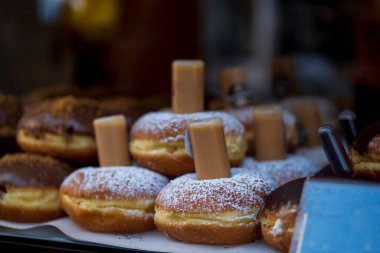 Berliner Pfannkuchen, a German donut, traditional yeast dough deep fried filled with chocolate cream or strawberry marmalade  and sprinkled with powdered sugar in showcase. Selective Focus.