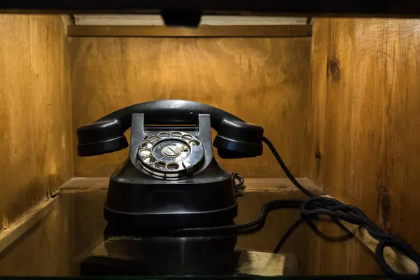 Antique Vintage Black Old Rotary Telephone on Wooden Background. Retro handset phone. Device with a dial.