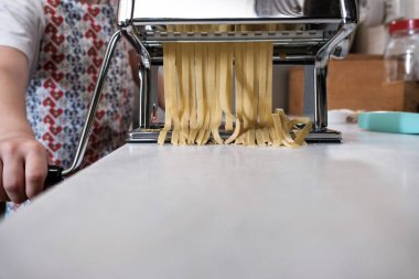Ev yapımı taze makarna makineyle kesiliyor, Tagliatelle makinesi çalışıyor.