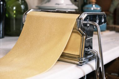 Hamur toplarken mutfak tezgahında taze makarna ve makarna makinesi. Makarna makinesiyle ev yapımı makarna hazırlıyorum..