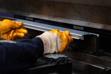 Çalışanların elleri ve çerçeve içindeki hidrolik makinenin baskı alanı ile hidrolik bir makinede metali büküyor ve şekillendiriyor..