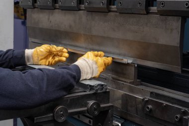 Çalışanların elleri ve çerçeve içindeki hidrolik makinenin baskı alanı ile hidrolik bir makinede metali büküyor ve şekillendiriyor..