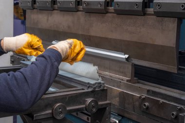 Çalışanların elleri ve çerçeve içindeki hidrolik makinenin baskı alanı ile hidrolik bir makinede metali büküyor ve şekillendiriyor..