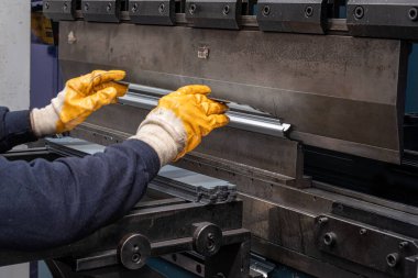 Çalışanların elleri ve çerçeve içindeki hidrolik makinenin baskı alanı ile hidrolik bir makinede metali büküyor ve şekillendiriyor..