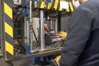 Otomasyon hidrolik baskı makinesi üretim hattı. Endüstriyel metal fabrikaları. Bir işçi hidrolik pres makinesinde ölüme baskı yapıyor..