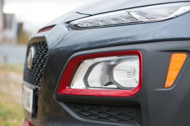 Modern prestijli arabanın ön farları yakın plan. Güzel bir arabanın farları. Koyu gri, kırmızı kenarlı. Ön tarafın bir kısmı, araba tanınmaz halde. Bir spor arabanın yön göstergeleri