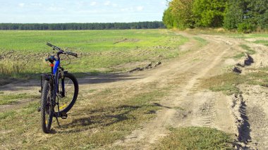 Ukrayna, Kiev bölgesi 19.09.2024. Dağ bisikleti. Bisiklet tarlada, yeşil çimlerle kaplı bir patikada duruyor. Bisiklet. Açık hava bisiklet aktiviteleri, seyahatler. Bisiklet, ekolojik ulaşım. Yazı