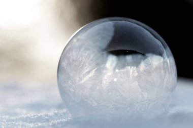 Karda donmuş bir baloncuk. Donmuş sabun köpüğünün üzerindeki buz gibi desenler çok güzel. Kış, soğuk arka plan. Donmuş baloncuk. Kar üzerinde sabun köpüğü. Yaklaş. Kış mevsimi, soğuk zamanlar. makro fotoğraf