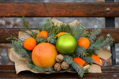 Parlak sulu mandalinalar, portakallar, çikolata, fındıklar ve Noel ağacında yeni yıl oyuncağı, yakın plan. El yapımı, narenciye buketi, meyve dalları ve Noel ağacı.