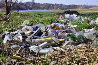 Kyiv, Ukrayna, 02.04.2017. Nehir kıyısındaki çöp yığınları, doğaya rastgele atılanlar. Plastik torba ve şişeler, kirli çimenlerdeki çöpler, doğa manzarası. İnsan kirliliği ekolojisi. Yazı