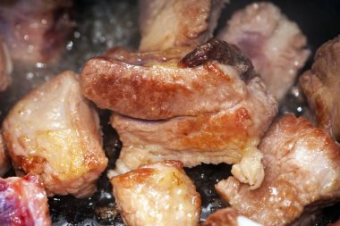 Kızarmış et parçaları, evdeki yağlı etten domuz eti. Tavada pişmiş yemek. Çok cesurca. Lezzetli et ürünleri kızartması. Kır usulü yemek pişirme, üst manzara. Et parçaları yağda kızartılır.