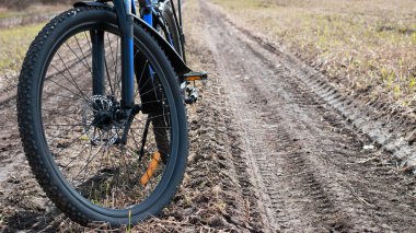 Dağ bisikletinin ön tekerleği. Dağ bisikleti. Saha yolunda duruyor. Bisiklet konsepti, tamir ya da bozulma, spor, açık hava aktiviteleri. Bisiklet yolda, ön tekerlek odakta. Metin için boşluk