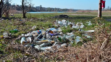 Kyiv, Ukrayna, 02.04.2017. Nehir kıyısındaki çöp yığınları, doğaya rastgele atılanlar. Plastik torba ve şişeler, kirli çimenlerdeki çöpler, doğa manzarası. İnsan kirliliği ekolojisi. Yazı