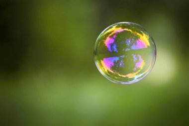 Yeşil arka planda çok renkli sabun köpüğü. Sabun köpüğü. Bahar ya da yaz aylarında yeşilde izole edilmiş. Refleks, detaylı, yakın plan. Çok renkli top sinekleri. Noel konsepti, çocukluk. Metin için boşluk