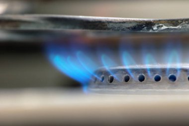 Gaz sobası yanıyor. Mavi alev yakın plan. Mavi ateş, mutfak sobasında doğal gaz yakar. Gaz yakıcılı çelik panel. Doğal kaynaklar kavramı, doğalgaz fiyat artışı, ekonomi