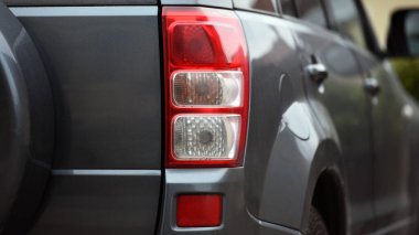 Güzel, modern spor araba. Aracın arkası tanınmaz halde. Prestijli otomobilin farları. Dur sinyali. Arkadan bak. Güzel bir arabanın farları. Gri renk, kırmızı fren lambası otomatik. yakın plan