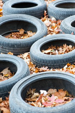 garbage from a heap of black old car tires among the trees in nature. environmental pollution. problems of ecology. car tires in autumn leaves, thrown into the forest. editorial, Ukraine, Kiev, 2021 clipart