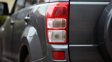 Güzel, modern spor araba. Aracın arkası tanınmaz halde. Prestijli otomobilin farları. Dur sinyali. Arkadan bak. Güzel bir arabanın farları. Gri renk, kırmızı fren lambası otomatik. yakın plan