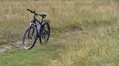 Bisiklet sahada duruyor. Bir dağ bisikleti kuru sonbahar otlarıyla dolu bir arazide duruyor. Bisiklet. Dağ bisikleti. Açık hava bisiklet aktiviteleri. Aktif dinlenme, spor. Kyiv, Ukrayna, 27.07.2024 yazı işleri.
