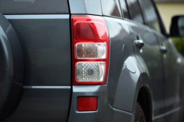 Güzel, modern spor araba. Aracın arkası tanınmaz halde. Prestijli otomobilin farları. Dur sinyali. Arkadan bak. Güzel bir arabanın farları. Gri renk, kırmızı fren lambası otomatik. yakın plan