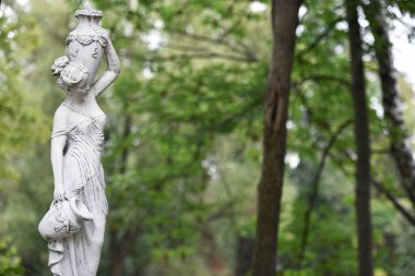 Bahar parkında bir kızın heykeli. Şehvetli bir parkta, yarı çıplak Yunan ya da İtalyan Rönesans kadınının şehir parkında vazosu olan eski bir heykeli. Yaz bahçesinde güneşli bir gün. yakın plan