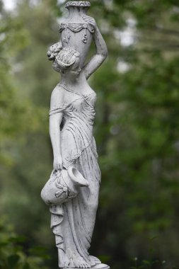Bahar parkında bir kızın heykeli. Şehir parkında yarı çıplak bir Yunan ya da İtalyan Rönesans kadınının vazosu olan eski bir heykel. bir sürahi su taşıyor. Alçıdan yapılmış kadın.