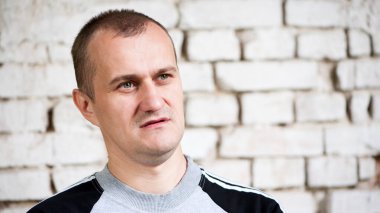 Genç Avrupalı. Erkek portresi. Adam tuğla duvarın önünde duruyor. fotoğraf, gülümseme, düşünceli, şaşırmış, kızgın, duygular, duygular. Açık tenli, sakallı. 30-40 yaşlarında bir adam. yakın plan