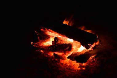 Yakacak odun yakar, gece ateş kömürü yakar. Ölen bir kamp ateşi çukurunda yanan kızgın kömürler. Geceleri kazıktaki kömürlerden portakal parlıyor. Siyah arkaplanda alevler