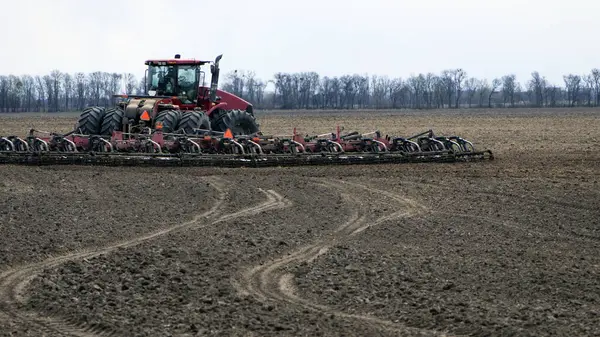 Kırmızı traktör tarlada dikiz aynasından, traktör tarlada tarla sürüyor. Büyük kırmızı traktör tarlada çalışıyor, hasat, iş, tarım. Toprak hazırlama, bahar mevsimi. Ukrayna