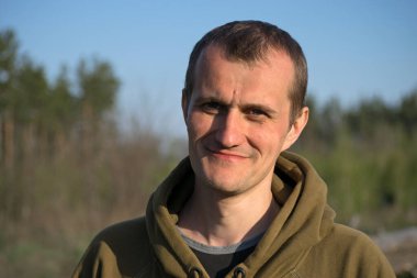 Erkek portresi. Doğanın arka planına karşı olan adam. fotoğraf, gülümseme, düşünceli, şaşırmış, kızgın, duygular, duygular. Açık tenli, sakallı. 30-40 yaşlarında bir adam. Yakın plan. Avrupa