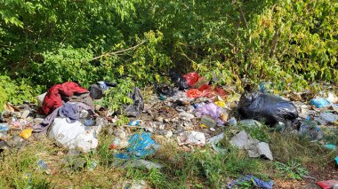 Kyiv, Ukrayna, 19.08.2024. Ormanda çöp yığınları, doğaya rastgele atılanlar. Pis kokulu hurda, plastik torba ve şişeler, doğanın kirli otlarının içindeki çöpler. Ekoloji. Yazı