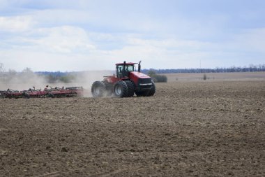 Kırmızı traktör, tarlada büyük bir traktör, hasat, çiftçilik. Yazın bir tarlada traktör, toprak hazırlığı. Çiftlik arazisinde traktör. Çiftlik arazisi, tarım endüstrisi.