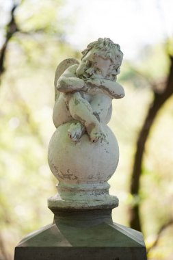 Parktaki melek heykeli. Kanatlı küçük çocuk. Spring Park 'taki aşk tanrısı heykeli. Tasarım için biblo, mermer üzgün bir melek topun üzerinde oturuyor. Aşk mevsimi
