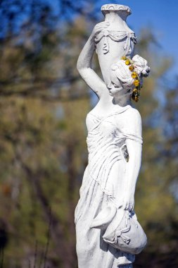 Bahar parkında bir kızın heykeli. Şehvetli bir parkta, yarı çıplak Yunan ya da İtalyan Rönesans kadınının şehir parkında vazosu olan eski bir heykeli. Yaz bahçesinde güneşli bir gün. Yakın çekim, vintage